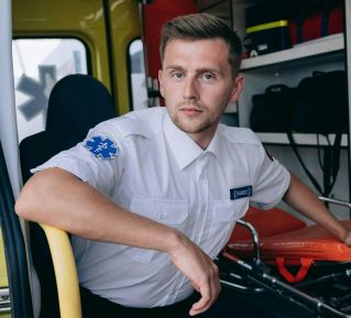 Male paramedic sitting inside an ambulance, ready for emergency response.